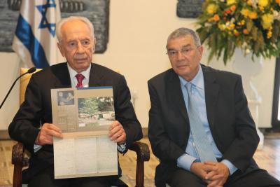 President Shimon Peres holding a copy of his father, Yitzhak Perski&#039;s testimony which formed the basis of the evidence for honoring Charles Coward as Righteous Among the Nations. He is seated next to Chairman of the Yad Vashem Directorate Avner Shalev.