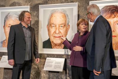 Angela Merkel mit Martin Schoeller und dem Holocaustüberlebenden Naftali Fürst in der Ausstellung