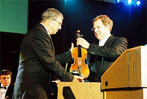 Shlomo Mintz (right), violinist and conductor, presents violin from the Holocaust period to Avner Shalev, Chairman of the Yad Vashem Directorate, during the opening ceremony marking Yad Vashem&#039;s Jubilee Year