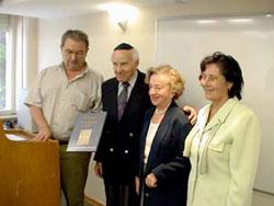 Prof. David Bankier (left), Head of the International Institute for Holocaust Research, presents Frida and David Weisz with a copy of the mahzor. Perla Hazan, Director of Yad Vashem&#039;s Latin-American Desk, is on the right