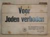 A wooden sign in Dutch with the words: “Forbidden for Jews”