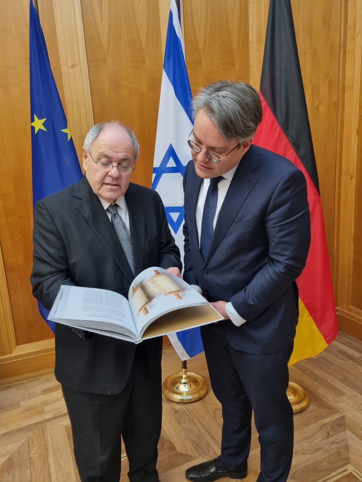 Dani Dayan überreicht dem Staatsminister im Auswärtigen Amt, Tobias Lindner, einen Artefaktkatalog der Yad Vashem-Synagoge