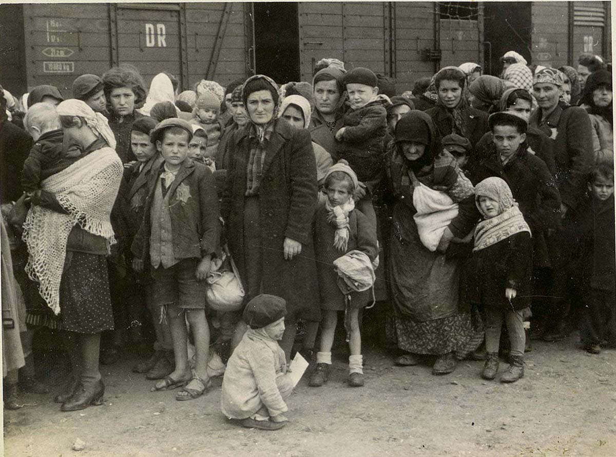 Frauen und Kinder auf dem Ankunftsbahnsteig in Birkenau, der als „Rampe“ bekannt ist. Die Juden wurden aus den Deportationszügen auf die Rampe geholt, wo sie einem Selektionsprozess unterzogen wurden – die meisten wurden sofort in den Tod  geschickt, andere zur Zwangsarbeit eingesetzt