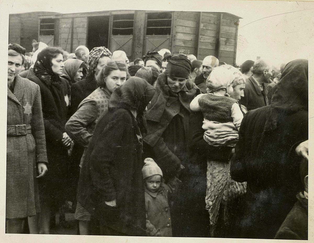 Femmes et enfants sur le quai d'arrivée de Birkenau, connu sous le nom de « rampe ». Les Juifs descendaient des trains de déportation vers la rampe, où ils passaient une sélection. Une partie étaient directement envoyés à la mort, les autres étaient envoyés aux travaux forcés