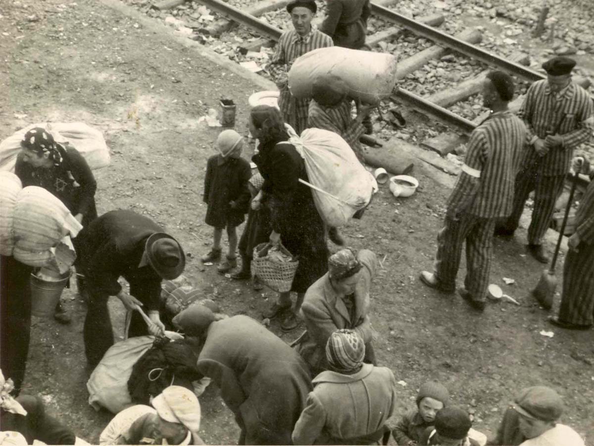Прибывшие в лагерь евреи перед селекцией. Такие массовые сцены были обычным явлением летом 1944-го, когда процесс уничтожения венгерских евреев достиг своего апогея. На заднем плане виден Крематорий II, куда посылали обреченных на смерть евреев. 