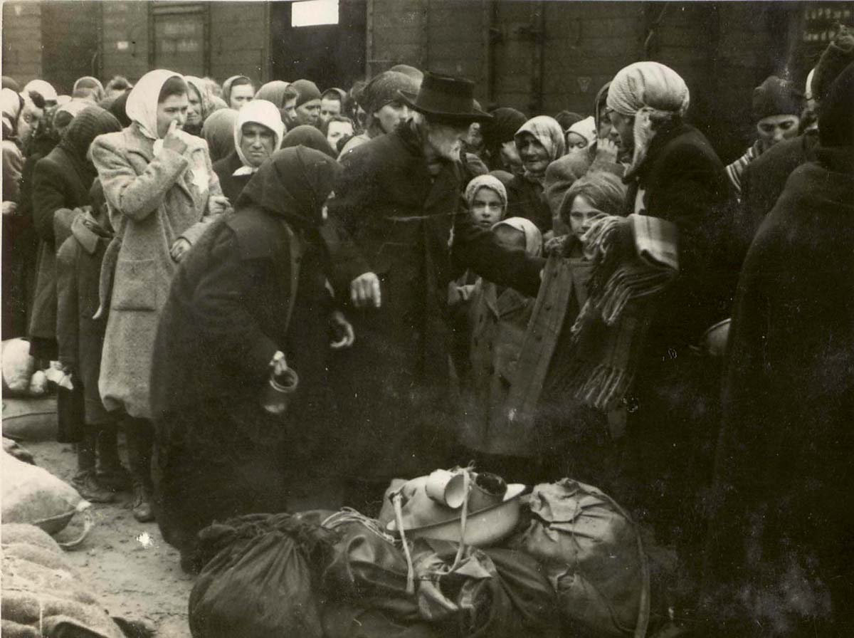 Женщины и дети на железнодорожной платформе Биркенау, известной как «рампа». Депортированные евреи проходили здесь селекцию: одних сразу же посылали на смерть, других отправляли на принудительные работы. 