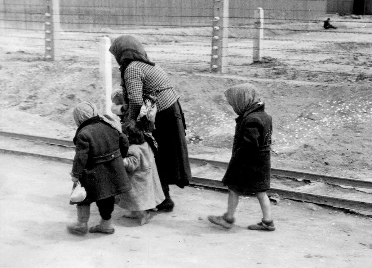 An old Jewish woman takes care of the little children as they are forced to walk towards the gas chambers