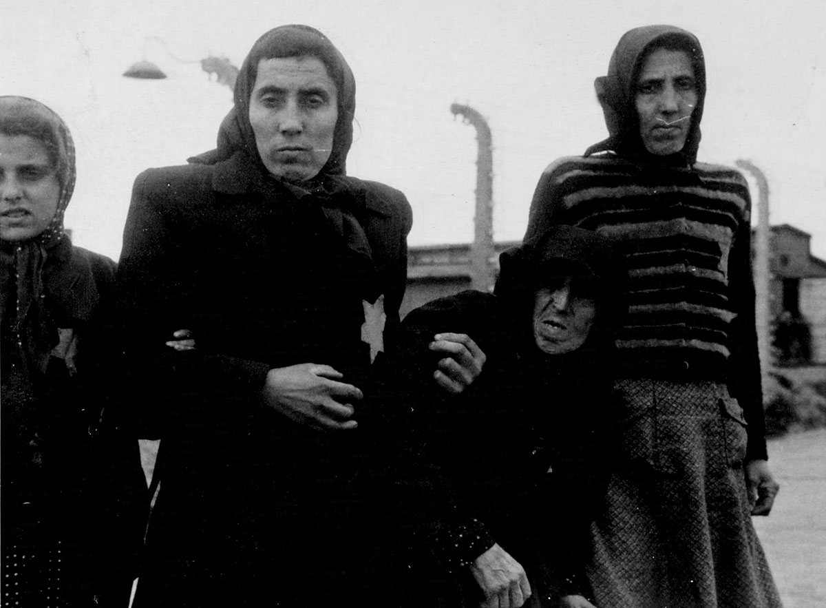 Femmes et enfants juifs forcés à marcher vers les chambres à gaz. Sur le quai attendent encore plusieurs wagons de train.