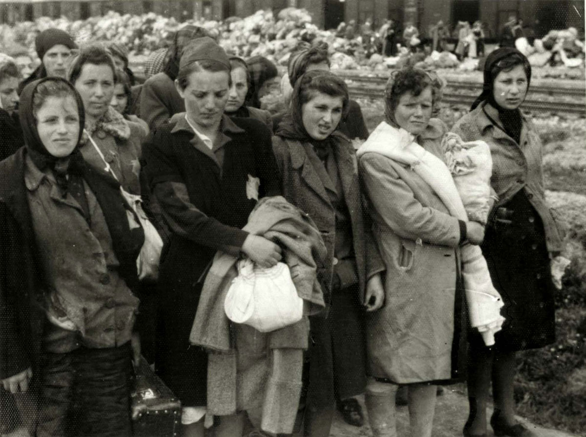 Jüdischen Frauen, die für die Zwangsarbeit selektiert wurden. Im Hintergrund die Habseligkeiten, die die Deportierten mitgebracht hatten