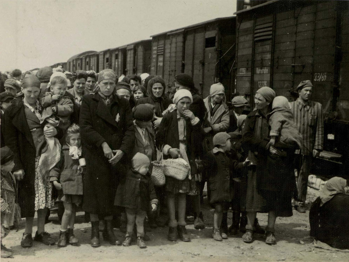 Jewish women and children on the selection platform. A prisoner from the "Kanada" kommando stands near the train