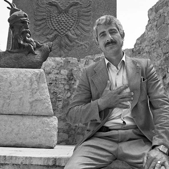 Enver Pashkaj vor einer Statue des albanischen Nationalhelden Skanderbeg