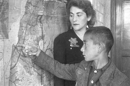 Teacher and pupil near a map of Eretz Israel in the ghetto, probably in a school in Marysin, Lodz, Poland