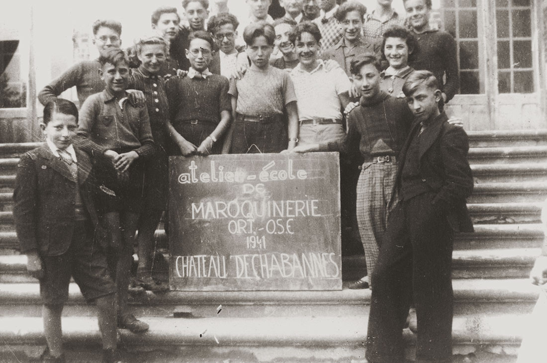 Jewish youngsters, students in an ORT leather workshop at the Château de Chabannes children's home, pose on the front staircase of the home that was sponsored by the OSE. Stephan Lewy is in the front row, center