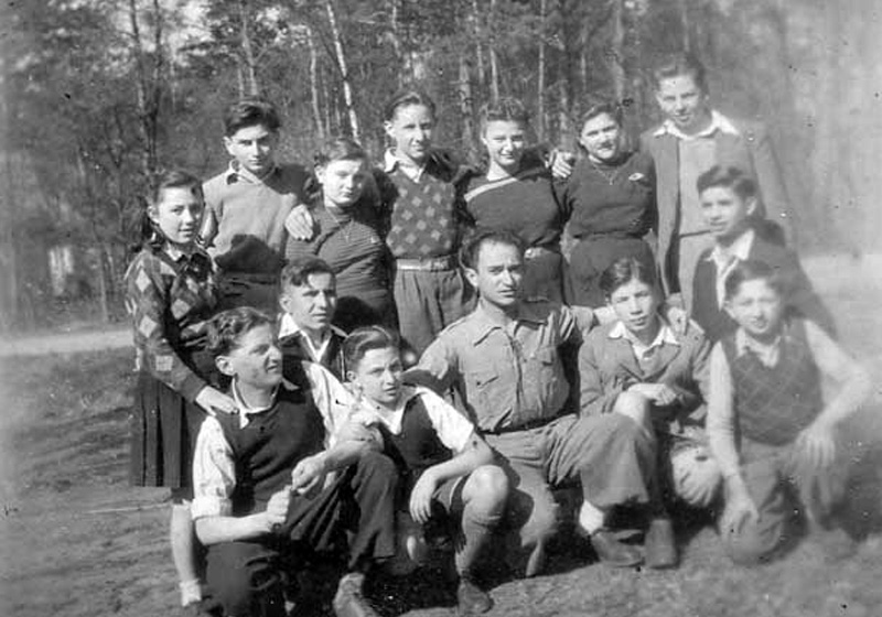 Counsellor Shimon Schechter (bottom center), and members of the older group of Dror Habonim youth movement at the "Ilania" children's village.  Apeldoorn, the Netherlands, 1948