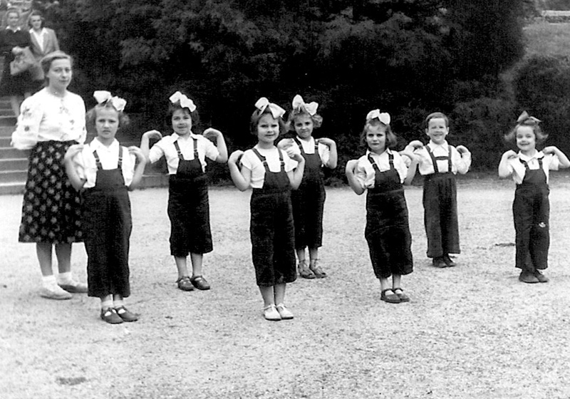 קבוצת בנות מבית הילדים בזבז'ה בשיעור התעמלות עם מדריכתן מירה כץ בעת שהיו באתר נופש. פולין, אוגוסט 1948