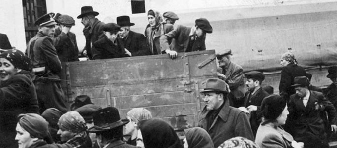 יהודים עולים על משאית תחת פיקוח איש מיליציה סלובקי בעת גירושם מסלובקיה, 1942