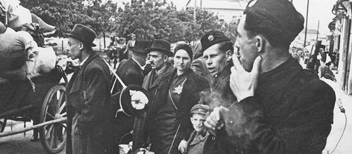 אנשי מיליציה סלובקית לצד יהודים הממתינים עם חפציהם לגירוש מסלובקיה, 1942