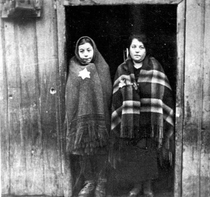 A woman and girl wearing the Yellow Star at the entrance to a house in Plonsk