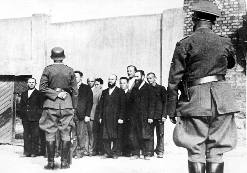 עו“ד עזריאל אברמוביץ, ראשון משמאל, בקבוצת יהודים אותם ריכזו אנשי אס-אס לפני שער בית הסוהר ה“לבן	“ בשוולי לפני רציחתם בירי ביערות קוז'י. 28-26 ביוני 1941