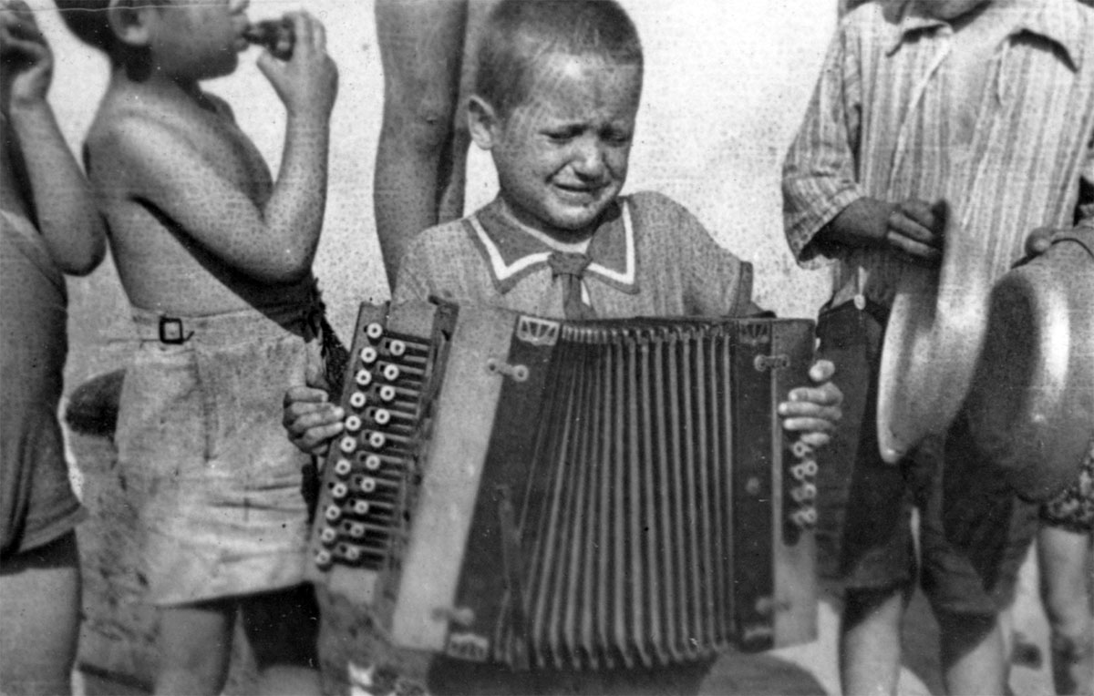 Lodz, Polonia. Un niño tocando un acordeón en el gueto, aparentemente en el sanatorio para niños en la comuna de niños en Marishin