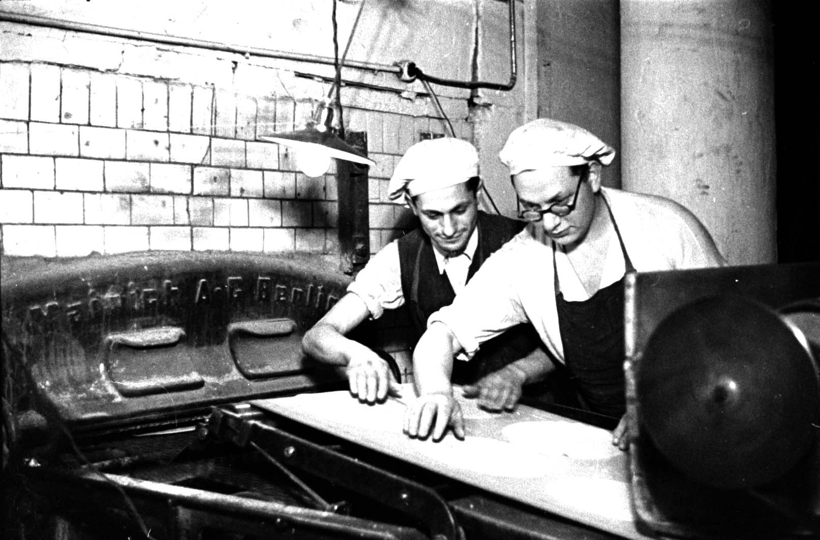 Dough being carried to the oven by conveyor belt at the Herzog matzah factory, Berlin, Germany, 1936.
