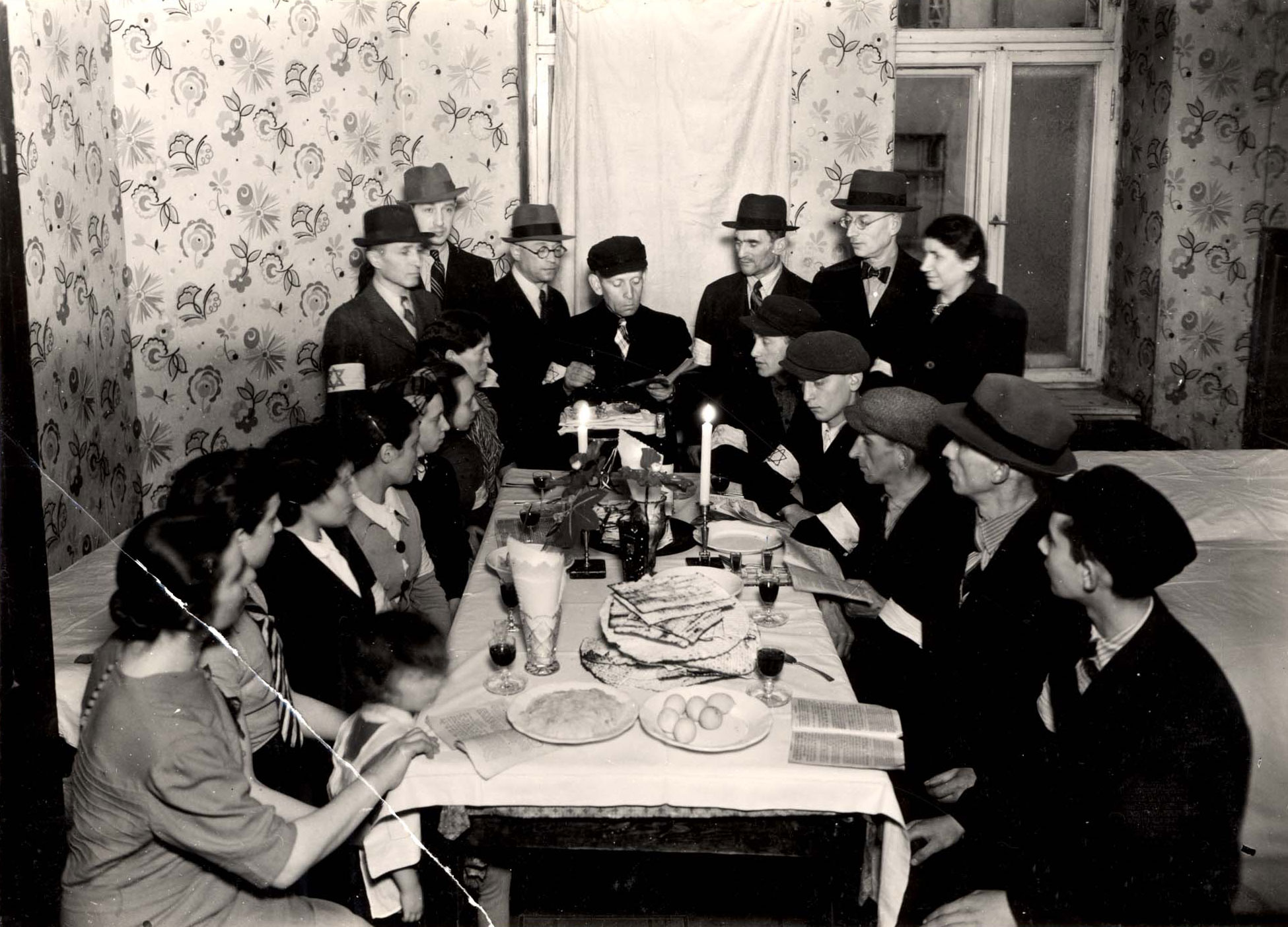 יהודים מסביב לשולחן הסדר קוראים את ההגדה של פסח בגטו ורשה, פולין