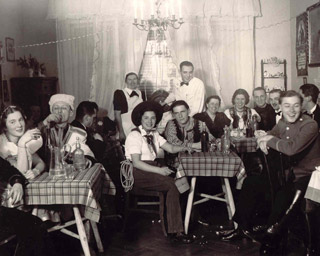 A private costume party, 1943. Béla Stollár, dressed as death, sits at the back row, fourth from the right. Éva Deák, dressed as a gypsy girl, sits next to him