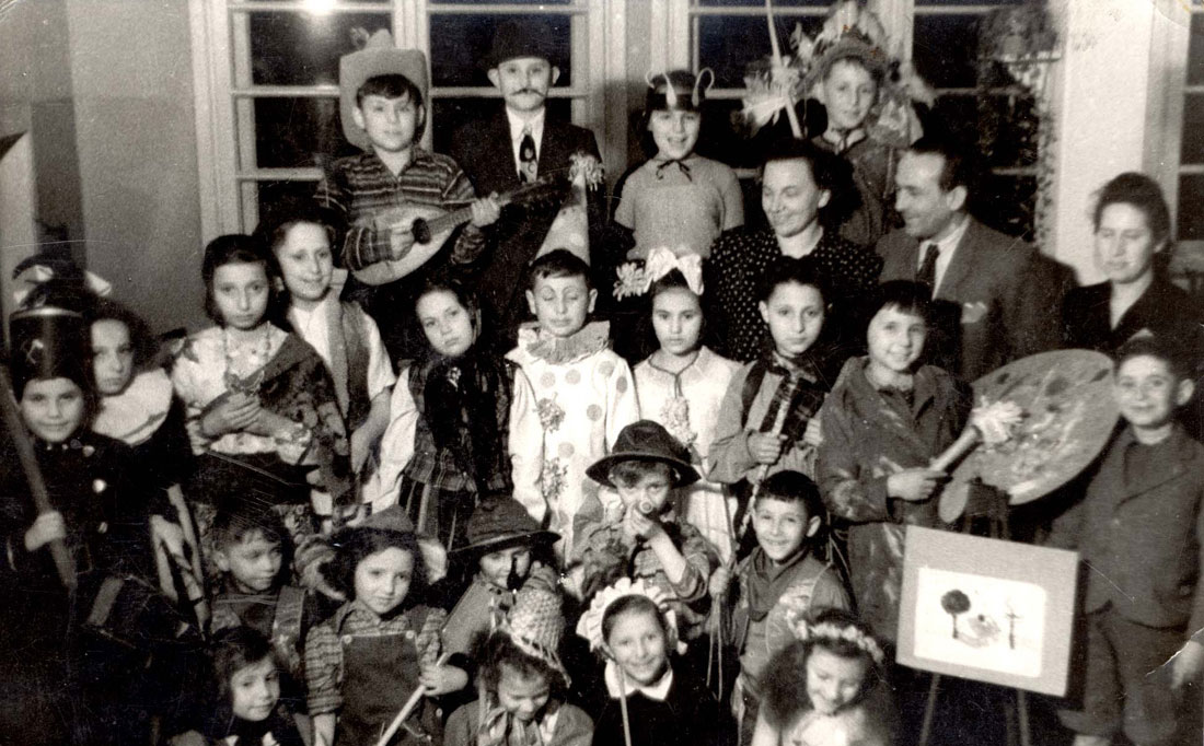 תמונה קבוצתית של הילדים והצוות של  בית הילדים היהודי באוטבוצק, פולין, במסיבת פורים שנערכה ב-1948
