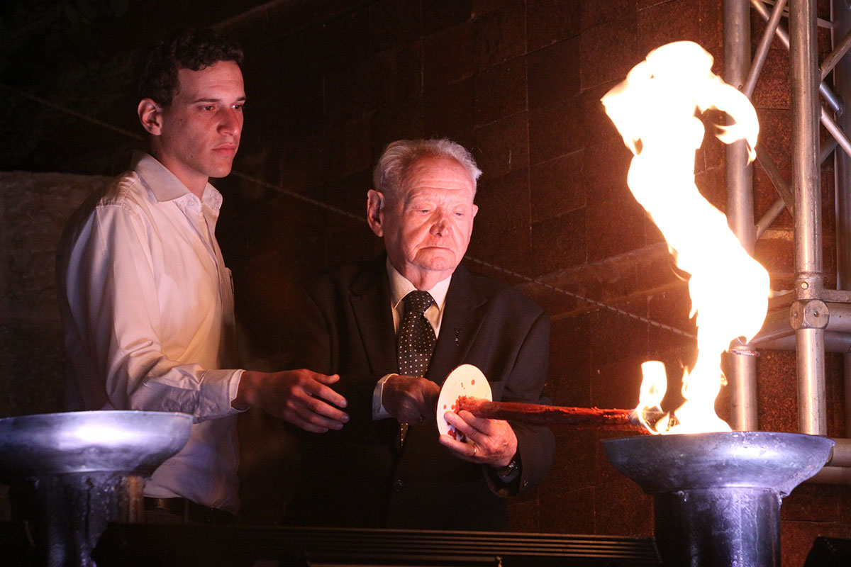 El sobreviviente del Holocausto Asher Aud encendiendo una de las seis antorchas durante la ceremonia