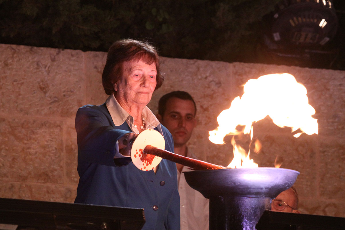 La sobreviviente del Holocausto Dita Kraus encendiendo una de las seis antorchas durante la ceremonia