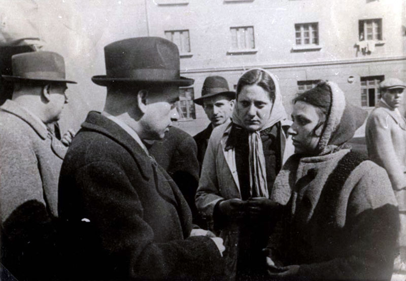 El “Comisario de Asuntos Judíos” Alexander Bélev hablando con mujeres judías durante una visita al sitio de concentración de los judíos, los depósitos de la fábrica de tabaco “Monopol”, Skopje, marzo de 1943