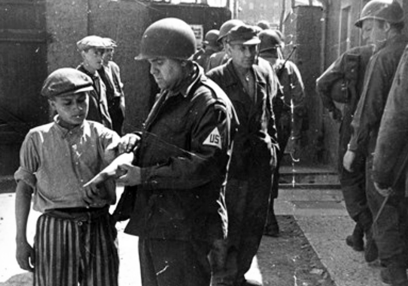 Un enfant rescapé de Buchenwald pris en charge par un soldat américain à la libération du camp