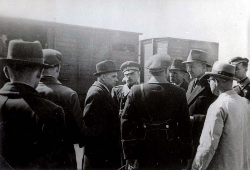מרץ 1943 - הקומיסר לענייני יהודים אלכסנדר בלב (שלישי משמאל) משוחח עם עוזריו בעת ביקור במקום ריכוז היהודים, מחסני מפעל הטבק 'מונופול' בסקופיה