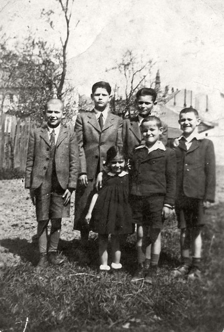 ילדי משפחת מנדל בחצר ביתם במונקאץ' ב-1943, לובשים בגדי שבת. בשורה העליונה, משמאל לימין: שמואל צבי (סנדור), דוד (טיבור), יעקב משה (יינו גינו). בשורה התחתונה, משמאל לימין: אסתר מלכה (ורה), יהודה (ליוס) ובצלאל ארנו 