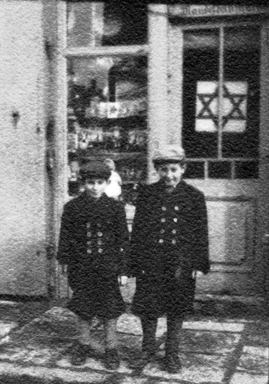 שני ילדים עומדים ליד חנות המסומנת במגן דוד בטשביניה