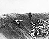 Лиепая, Латвия, 15-17/12/1941. Латвийский полицейский идет вдоль расстрельного рва, заполненного трупами казненных женщин и детей.