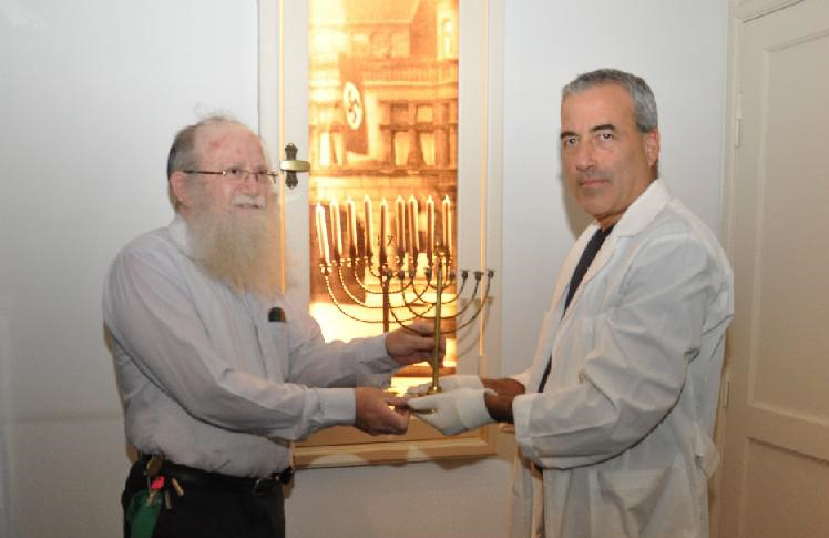 Иегуда Мансбах (слева) получает ханукальную менору от Михаэля Таля, директора отдела коллекции артефактов Яд Вашем